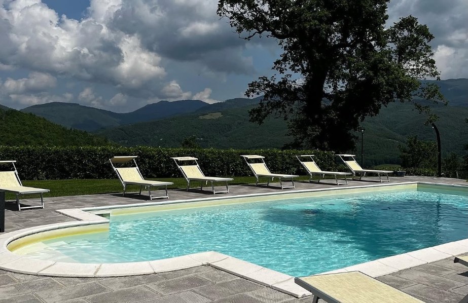 Piscina con i lettini, la grande quercia e le montagne del Casentino
