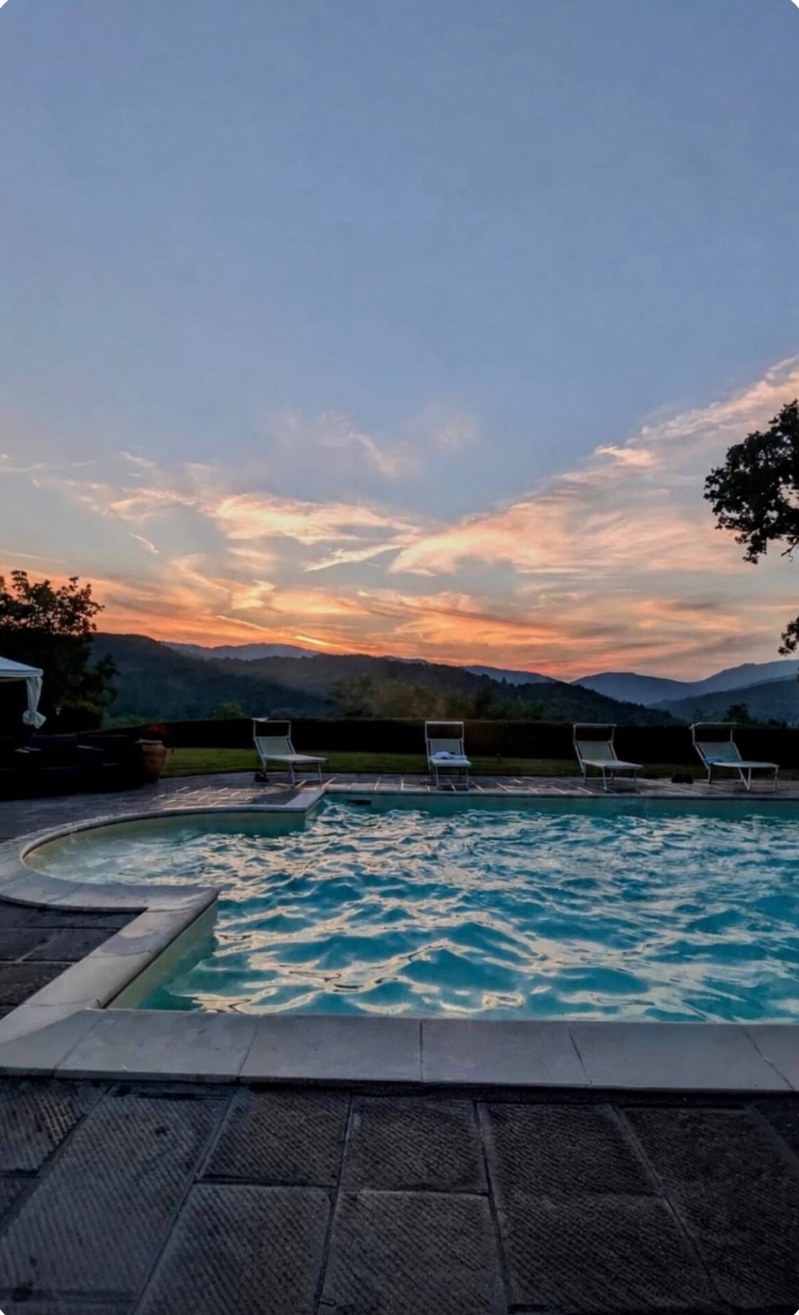 La piscina al tramonto, con i lettini e le montagne del Casentino sullo sfondo